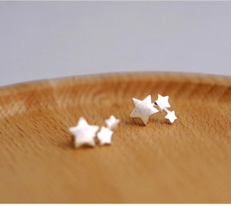 May include: Two pairs of silver star stud earrings. Each pair has three stars of varying sizes.