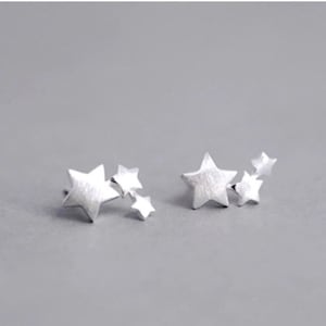 May include: Two silver star-shaped earrings with multiple smaller stars attached to the larger star.