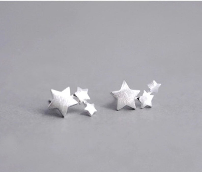May include: Two silver star-shaped earrings with multiple smaller stars attached to the larger star.