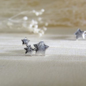 May include: Three silver star-shaped charms clustered together. The stars are textured and have a brushed finish.