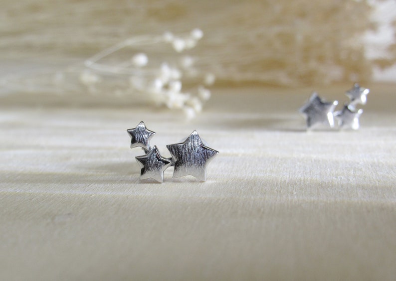 May include: Three silver star-shaped charms clustered together. The stars are textured and have a brushed finish.