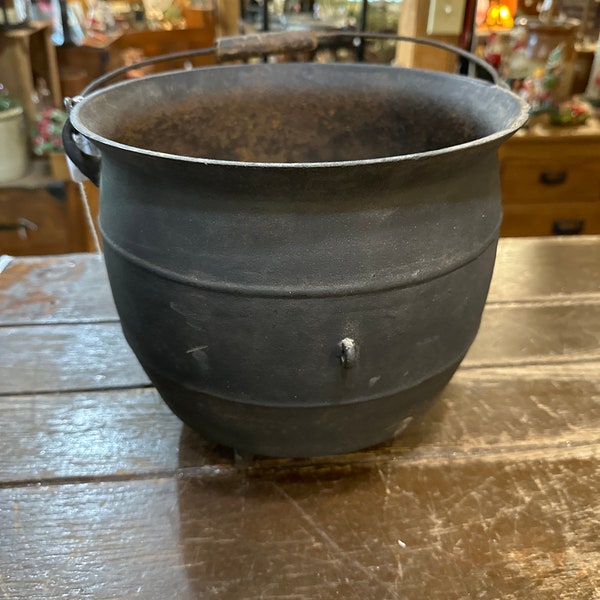 Antique cast iron kettle with claw feet and wooden handle