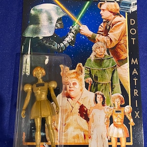 May include: A vintage Spaceballs Dot Matrix action figure, still in its original packaging. The packaging features images of characters from the movie, including a gold-colored robot figure. The card reads "Spaceballs" at the top.