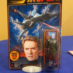 May include: A Firefox Stealth Air Superiority Fighter action figure in original packaging. The card features a fighter jet illustration, a portrait of a pilot, and text including Thought-Control Fighter Pilot and Firefox Mission Series.