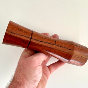Mans hand holding single curved tapered Jarrah grinder