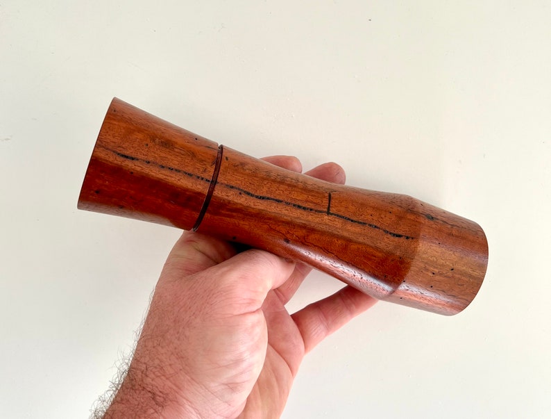 Mans hand holding single curved tapered Jarrah grinder