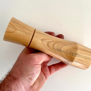 Mans hand holding single curved tapered Norfolk island pine grinder