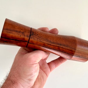 Mans hand holding single curved tapered Jarrah grinder