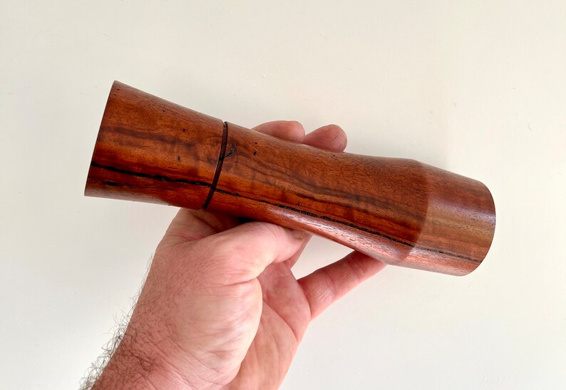 Mans hand holding single curved tapered Jarrah grinder