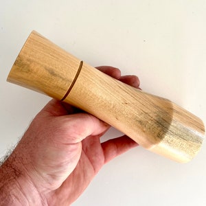 Mans hand holding single curved tapered Norfolk island pine grinder