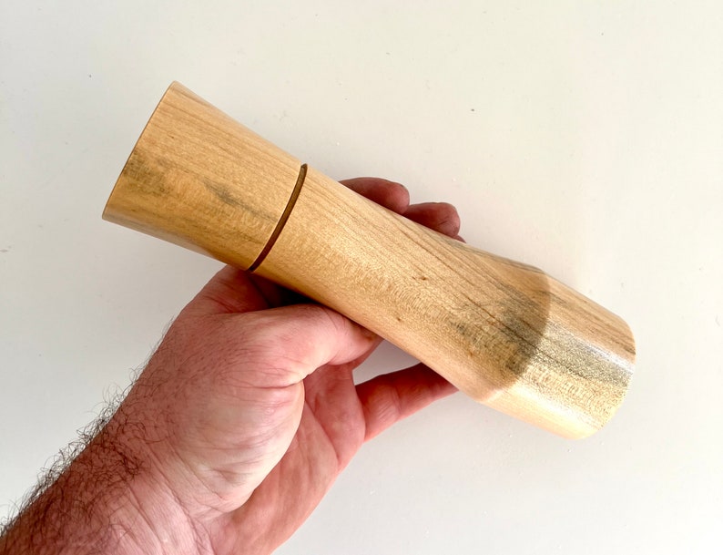 Mans hand holding single curved tapered Norfolk island pine grinder