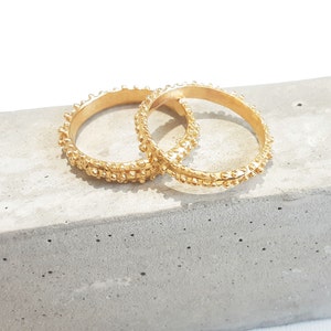 Op de afbeelding: Twee gouden ringen met een getextureerd oppervlak. De ringen liggen op elkaar.
