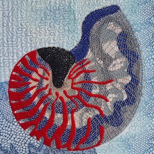 Könnte beinhalten: Textilkunstwerk, das eine Nautilusmuschel darstellt. Die Muschel ist mit schwarzen, roten, blauen und grauen Fäden gestickt. Der Hintergrund ist ein strukturiertes blaues Gewebe mit einem zarten, spitzenartigen Muster.
