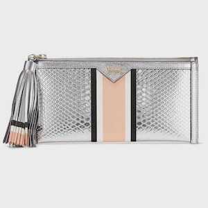 May include: Silver clutch with a snakeskin pattern, a vertical stripe design in black, white, and peach, and a silver tassel. The clutch has a zipper closure and the brand name is visible.