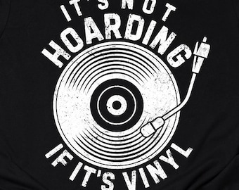 May include: Black t-shirt with a white graphic of a vinyl record and a turntable needle. The text reads "IT'S NOT HOARDING IF IT'S VINYL". The shirt has a crew neck and short sleeves.