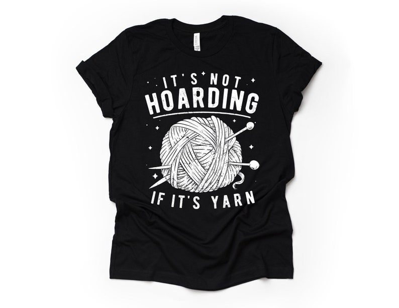 May include: Black t-shirt with a white graphic of a ball of yarn and knitting needles. The text "It's not hoarding if it's yarn" is printed on the shirt.
