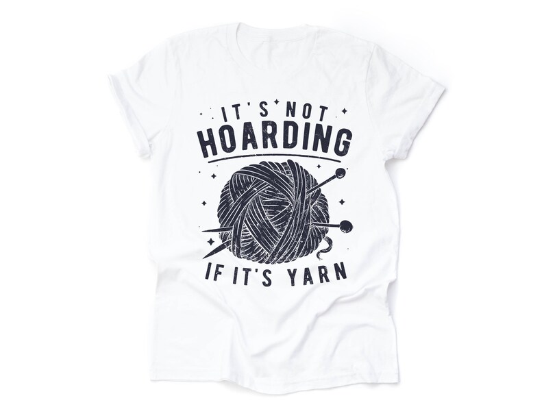 May include: White t-shirt with a black and white graphic of a ball of yarn and knitting needles. The text "It's not hoarding if it's yarn" is printed on the shirt.