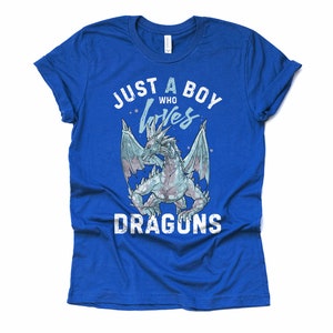 May include: A royal blue t-shirt with a white distressed graphic that says "Just a boy who loves dragons". The graphic features a blue and white dragon with wings spread.