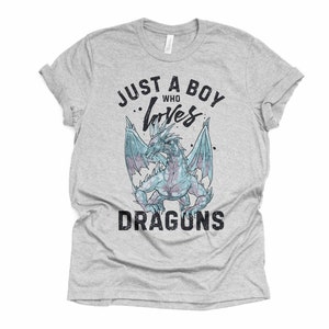 May include: A gray t-shirt with the text "Just a boy who loves dragons" in black. A blue dragon with wings is in the center of the text.