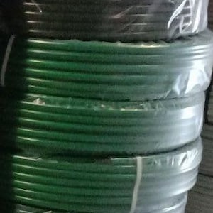 K&ouml;nnte beinhalten: Nahaufnahme einer Rolle gr&uuml;nes und schwarzes Bew&auml;sserungsschlauch. Der Schlauch ist aufgerollt und in Plastik verpackt.