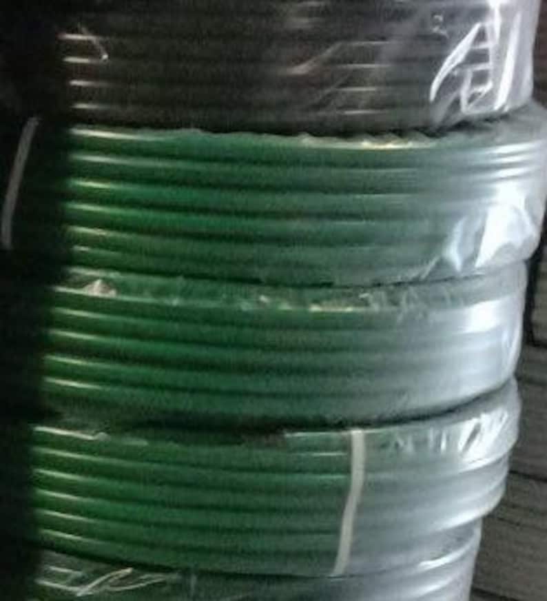 K&ouml;nnte beinhalten: Nahaufnahme einer Rolle gr&uuml;nes und schwarzes Bew&auml;sserungsschlauch. Der Schlauch ist aufgerollt und in Plastik verpackt.
