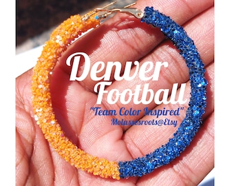 Può includere: Orecchini a cerchio glitterati nei colori della squadra di football dei Denver Broncos. Gli orecchini sono metà arancioni e metà blu, con il testo "Denver Football" e "Team Color Inspired".