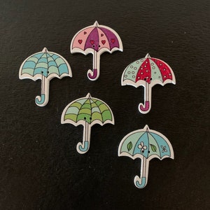 May include: Six wooden buttons shaped like umbrellas with different colorful patterns. The umbrellas are in various colors, including pink, red, blue, green, and white.