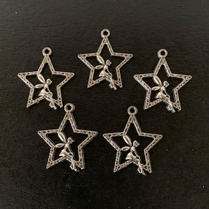 May include: Five silver star-shaped charms with a fairy sitting inside each star.