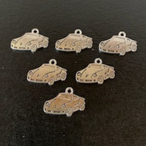 May include: Six silver charms shaped like vintage cars. Each charm has a detailed outline of a car with a rounded body and a small windshield.