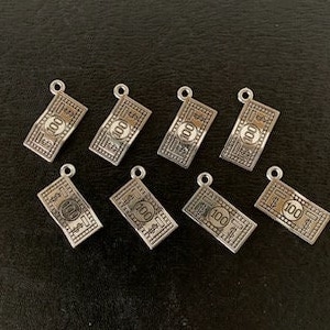 May include: Eight silver-toned charms shaped like dollar bills with the number "100" printed on them.