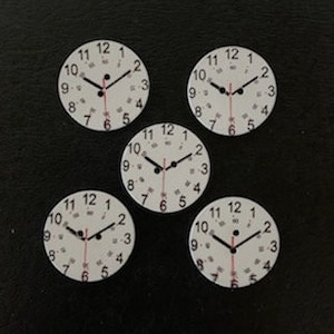 May include: Five white clock faces with black numbers and hands. The clock faces are all the same size and have a black outline.