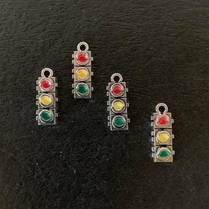 May include: Four silver charm pendants shaped like traffic lights with red, yellow, and green glass beads.