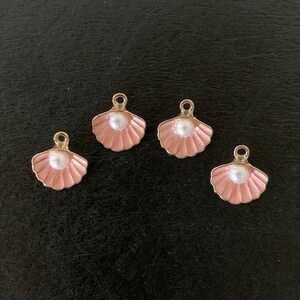 May include: Four pink seashell charms with a pearl accent. Each charm has a gold loop for attaching to jewelry or other crafts.