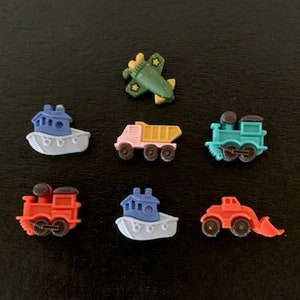 May include: A set of seven colorful plastic toy vehicles, including a blue boat, a red truck, a blue train, a red train, a blue boat, a yellow dump truck, and a green airplane.