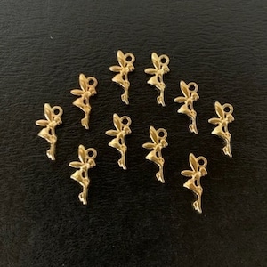 May include: A collection of 10 gold-toned metal charms featuring a fairy design. The charms are small and delicate, perfect for adding a touch of whimsy to jewelry or crafts.