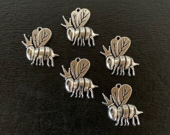 May include: Five silver bee charms with detailed wings and a crown on their heads.