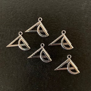May include: Six silver protractor charms with a textured surface. The charms are in the shape of a triangle with a semi-circle on the bottom.