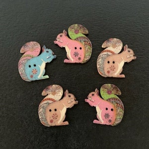 May include: Five wooden buttons shaped like squirrels with colorful patterned designs. The squirrels are in various poses, including sitting, standing, and running. The buttons are approximately 1 inch in diameter.