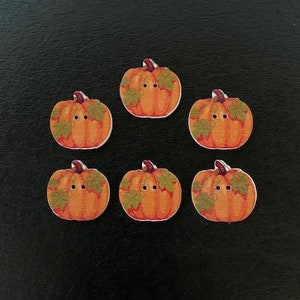 May include: Six wooden pumpkin buttons with brown stems and green leaves. The pumpkins are orange with brown details.