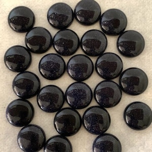 May include: A collection of 20 round, dark blue, sparkly cabochons. The cabochons are smooth and have a speckled appearance.