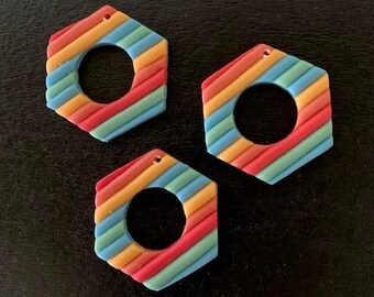 May include: Three hexagonal shaped rainbow striped clay earrings with a hole in the center for hanging.