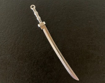 May include: A silver-colored miniature sword pendant with a detailed handle.