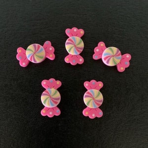 May include: Five pink candy-shaped buttons with a colorful swirl design. The buttons are about 1 inch in diameter.