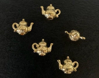 May include: Five gold-colored teapot charms with intricate details. The charms are small and perfect for adding a touch of whimsy to jewelry or crafts.