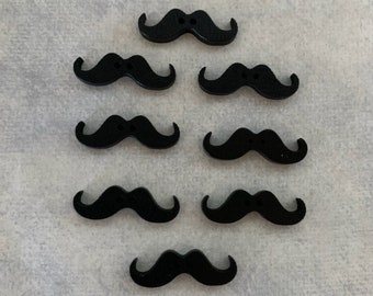 May include: A collection of eight black mustache-shaped buttons. Each button has two small holes for sewing. The buttons are arranged on a light gray textured surface. These buttons are ideal for craft projects.
