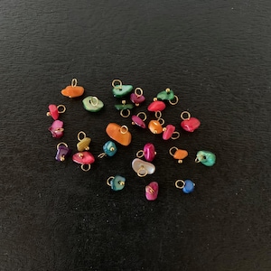 May include: Assortment of colorful, small, irregular shaped stones with gold jump rings. The stones are in shades of pink, orange, green, blue, and purple.