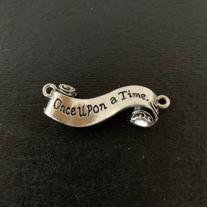 May include: Silver charm with a scroll design that reads "Once Upon a Time."