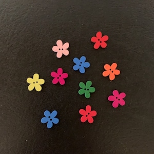 May include: Assortment of ten colorful flower-shaped buttons. The buttons are made of wood and have a flat back. The colors include pink, red, yellow, blue, green, and orange.