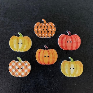 May include: Six wooden pumpkin-shaped buttons in various colors and patterns. The buttons feature orange, yellow, and red hues, with designs including polka dots and plaid. Each button has a green stem and two small holes for sewing.