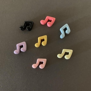 May include: Seven plastic music note buttons in various colors, including black, pink, light blue, purple, and yellow.